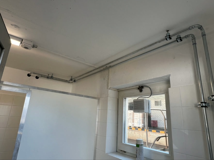 Rohrleitungen Aufputz – Sanitärinstallation – Aufputz-Rohrleitungen in Edelstahl mit Pressfittings für Warm- und Kaltwasser. Saubere Leitungsführung entlang Decke und Wand.