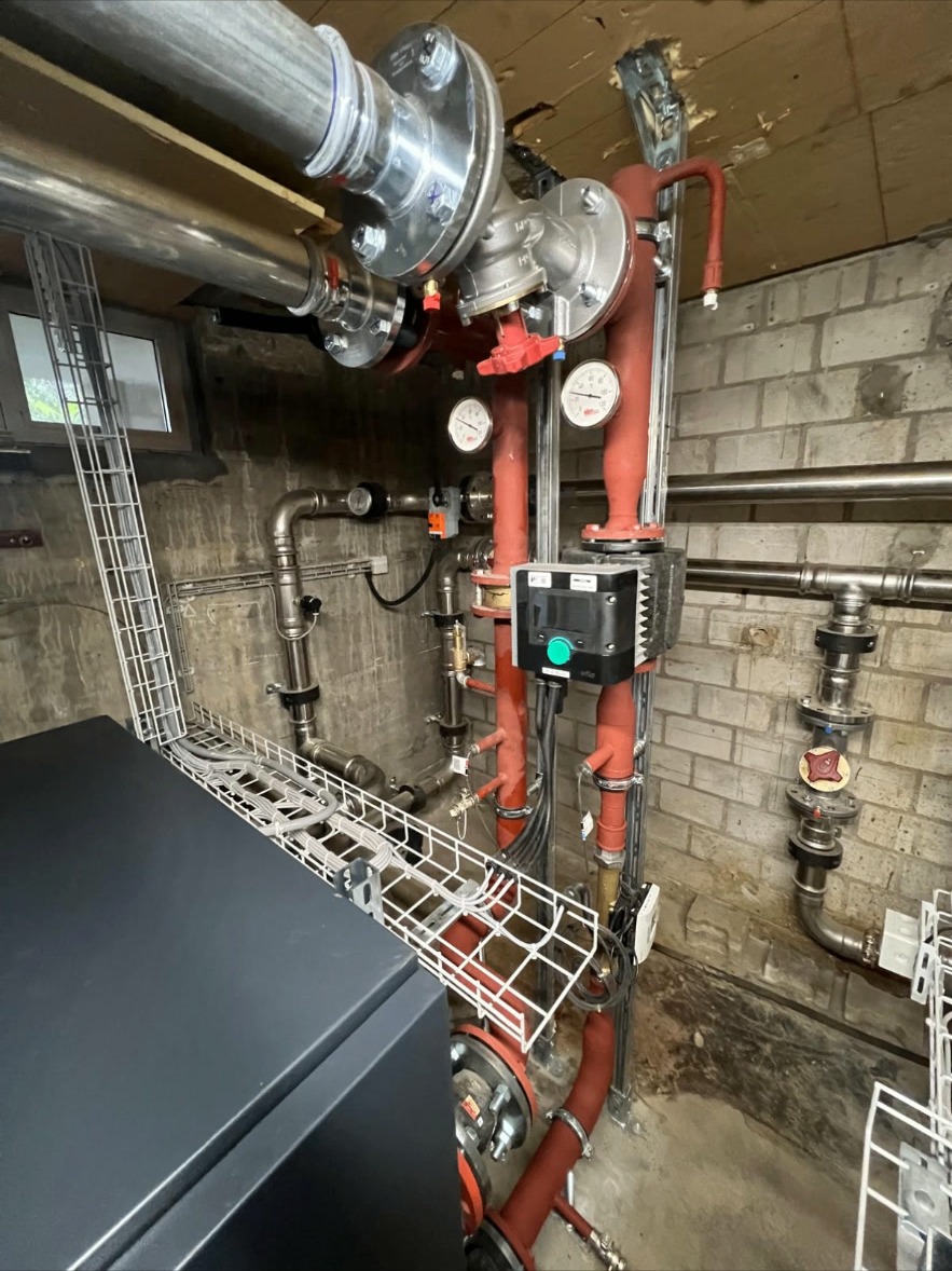Pumpengruppe mit Wilo-Regelung – Heizungs-Pumpengruppe mit Wilo-Regelung, Manometern und isolierten Leitungen für die Wärmeverteilung im Technikraum.